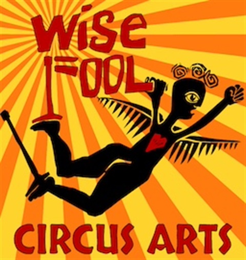 Image Reading: Wise Fool Circus Arts. The image contains a drawing of a human form with wings and a heart in the center. The background is striped.