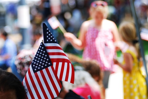 4th of July Stock Image showing small flags in the foreground and people in the background out of focus