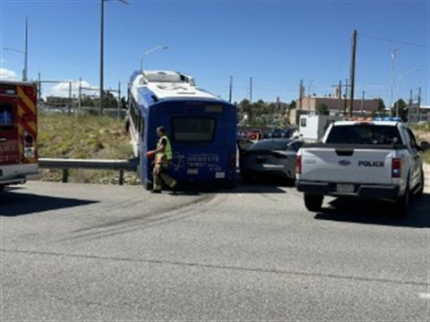 Photo of the Atomic City Transit bus over the guard rail and the back of the a police vehicle.  
