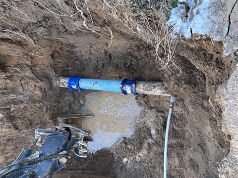 Blue water pipe in the bottom of a muddy, deep hole