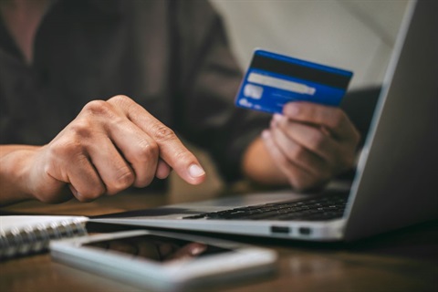 photo showing a hand holding a credit card in front of a computer screen