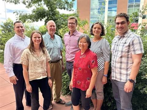 Seven members of the Sustainability Board pose in front of the Municipal Building paito on a spring day. 