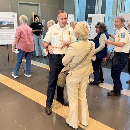 Wildfire Chief Kelly Sterna speaking with a community member at Reflections on the Cerro Grande Fire: 25 Years Later event